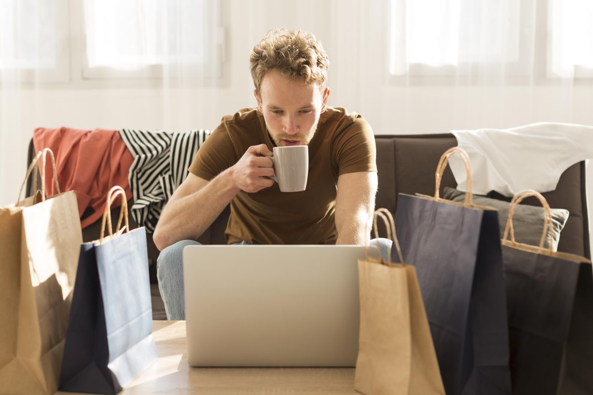 Homem conferindo loja online segurando xícara de café